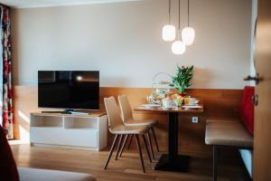 法克湖畔艾格的住宿－艾姆西公寓酒店，客厅配有桌椅和电视
