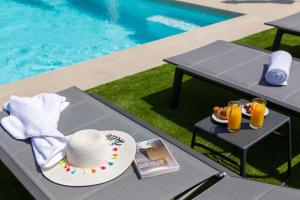 a table with a hat and a plate of food next to a pool at Luxury Seaside Villa L'Amour with pool in Sibenik - Zaboric in Zaboric