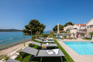 a row of tables by the pool at a resort at Luxury Seaside Villa L'Amour with pool in Sibenik - Zaboric in Zaboric