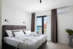 a bedroom with a large white bed with a large window at Luxury Seaside Villa L'Amour with pool in Sibenik - Zaboric in Zaboric +33 photos