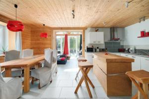 una cucina con soffitto in legno, tavolo e sedie di Piscine Spa et Sauna Privé a Uzemain