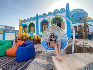 a woman sitting in a chair in front of a building at Kato Dool Wellness Resort in Aswan