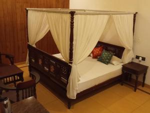 a bedroom with a canopy bed and a table at Shantitheeram Ayurveda Lakeside Heritage Resort in Alleppey
