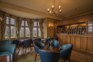 a restaurant with blue chairs and a bar at Cragwood Country House Hotel in Windermere