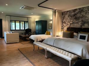 una camera d'albergo con due letti e una panca di The Stanley and Livingstone Boutique Hotel a Victoria Falls