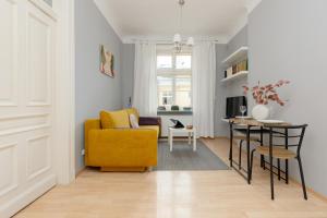 a living room with a yellow couch and a table at Sunny Studio Lwowska Street Metro by Renters in Warsaw