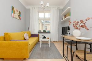 a living room with a yellow couch and a table at Sunny Studio Lwowska Street Metro by Renters in Warsaw