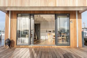 une maison avec des portes coulissantes en verre sur une terrasse dans l'établissement Surla Houseboat De Saek with tender, à Monnickendam