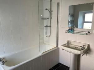 Un baño blanco con ducha y lavabo. en Tenby Cottage with Parking, en Tenby
