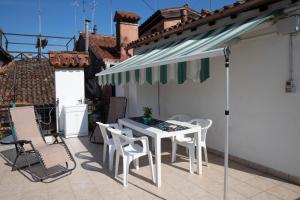 uma mesa branca e cadeiras sob um guarda-sol num pátio em Casa Loredana em Veneza