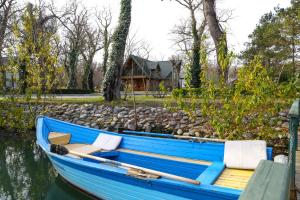 a blue boat sitting in the water next to a house at RIVER INN RESORT AND SPA in Nabran