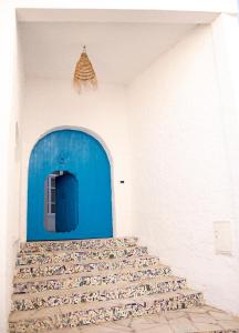 une porte bleue dans une pièce blanche avec des oiseaux au sol dans l'établissement Dar Yessine Boutique Hôtel, à Sousse