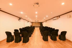 an empty room with black chairs on a wooden floor at Yuvraj Heritage Shelter Resort in Hosa Kannambādi