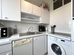 - une cuisine blanche avec un lave-linge et un évier dans l'établissement 107 - Appartement 2 chambres au Sables-D'Or avec vue mer, à Fréhel