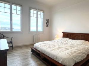 une chambre avec un grand lit et deux fenêtres dans l'établissement 107 - Appartement 2 chambres au Sables-D'Or avec vue mer, à Fréhel
