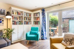 a living room with a green chair and bookshelves at Terraced Bermondsey House in London