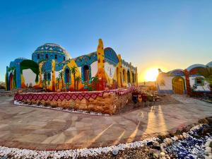 a mosque in the desert with the sun setting behind it at Kato Dool Wellness Resort in Aswan