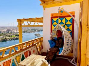 a woman sitting in a swing on a balcony overlooking the river at Kato Dool Wellness Resort in Aswan