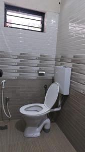 een badkamer met een wit toilet en een raam bij Aptha Ayurveda in Kadikkād