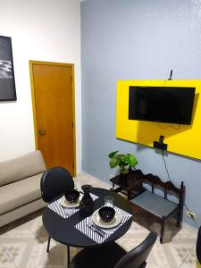 uma sala de estar com uma mesa e uma televisão na parede em Flat Duplo para sua conexão em Guarulhos