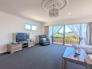 a living room with a tv and a couch and a table at Available Now! Family home near Redwood Forest in Rotorua