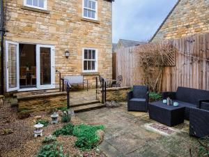 a patio with couches and chairs in front of a house at Bumble Cottage in Chipping Campden