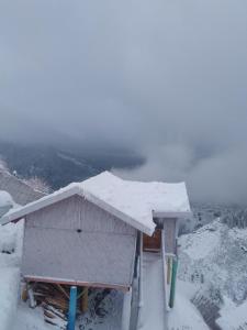 a building covered in snow on top of a mountain at THE WONDERLAND COTTAGES & Cafe in Nārkanda
