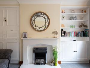 a living room with a fireplace and a mirror at Bumble Cottage in Chipping Campden +17 photos