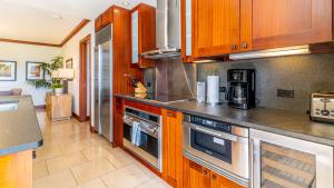 a kitchen with wooden cabinets and stainless steel appliances at Ko Olina Beach Villas B403 in Kapolei