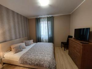 a bedroom with a bed and a flat screen tv at SAS Apartamenty Green Park in Szczecin
