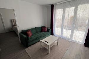 uma sala de estar com um sofá verde e uma mesa de centro em Bondy11 - Gare Paris Disney em Bondy