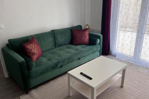 um sofá verde numa sala de estar com uma mesa de centro em Bondy11 - Gare Paris Disney em Bondy