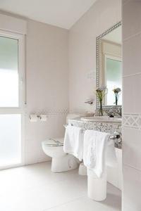 a bathroom with a sink and a toilet and a mirror at Hotel Rey Arturo Burgos in Villagonzalo-Pedernales