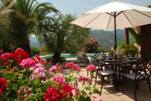 a patio with a table and umbrella and flowers at Stunning Mountain Views with Secluded Private Pool in La Roquette-sur-Var