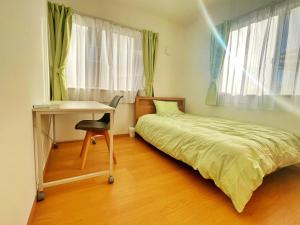 een kleine slaapkamer met een bed, een bureau en een tafel bij グローカル春日居温泉 in Fuefuki