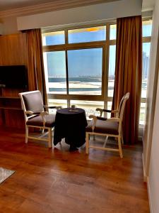 MIRADOR HOTEL في المنامة: غرفة معيشة مع طاولة وكراسي ونافذة كبيرة