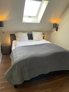 a bedroom with a large bed with a skylight at Residence De Kaaipoort appartementen in Aardenburg