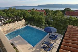 a swimming pool with two chairs and an umbrella at Welcome to Island Krk! in Linardići