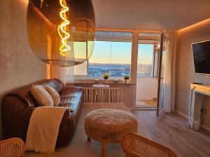 a living room with a leather couch and a large window at Stylische Sunset-Wohnung in Augsburg