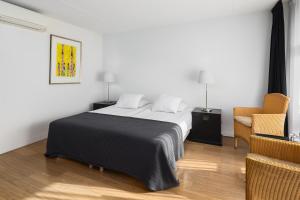 ein Schlafzimmer mit einem großen Bett und einem Stuhl in der Unterkunft Strandhotel Domburg in Domburg
