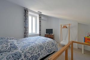 a bedroom with a bed and a window and a television at La Cigale - Vieux Village - Charmante Maisonnette climatisée avec Jardin in Villeneuve-lès-Avignon +48 photos