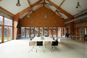 La Ferme Des Ailleurs في Arleux-du-Nord: قاعة اجتماعات مع طاولة وكراسي كبيرة