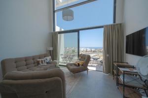 un soggiorno con divano, sedie e una grande finestra di Modern and spacious apartment with beautiful roof terrace and sea view a Kyrenia