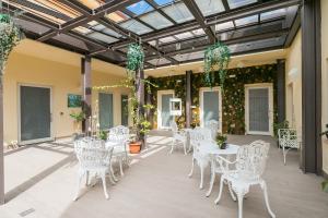 un patio avec des chaises blanches, des tables et des plantes dans l'établissement Borghetto Guest House, à Rome