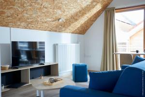 uma sala de estar com um sofá azul e uma televisão em La Ferme Des Ailleurs em Arleux-du-Nord