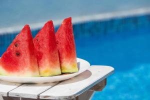 a plate of watermelon on a table next to a pool at Summer House with Heated Swimming Pool in Mostar