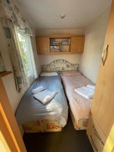 2 łóżka pojedyncze w niewielkim pokoju z oknem w obiekcie 2 bedroom cosy caravan w mieście Borth