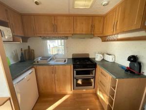 una cucina con armadi in legno e piano cottura. di 2 bedroom cosy caravan a Borth
