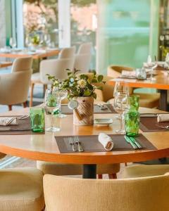 a wooden table in a restaurant with glasses and flowers at Douro Castelo Signature Hotel & Spa in Lamego