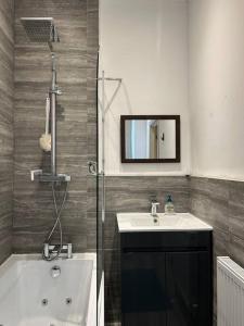 uma casa de banho com uma banheira, um lavatório e um espelho. em Ensuite Room with Private Bathroom at Walsall em Walsall